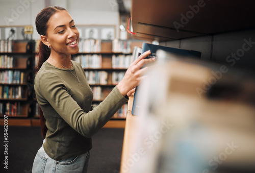 Photography Student search bookshelf for books in library for education, knowledge and learning about history, philosophy and language study