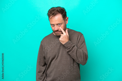 Middle age caucasian man isolated on blue background showing something