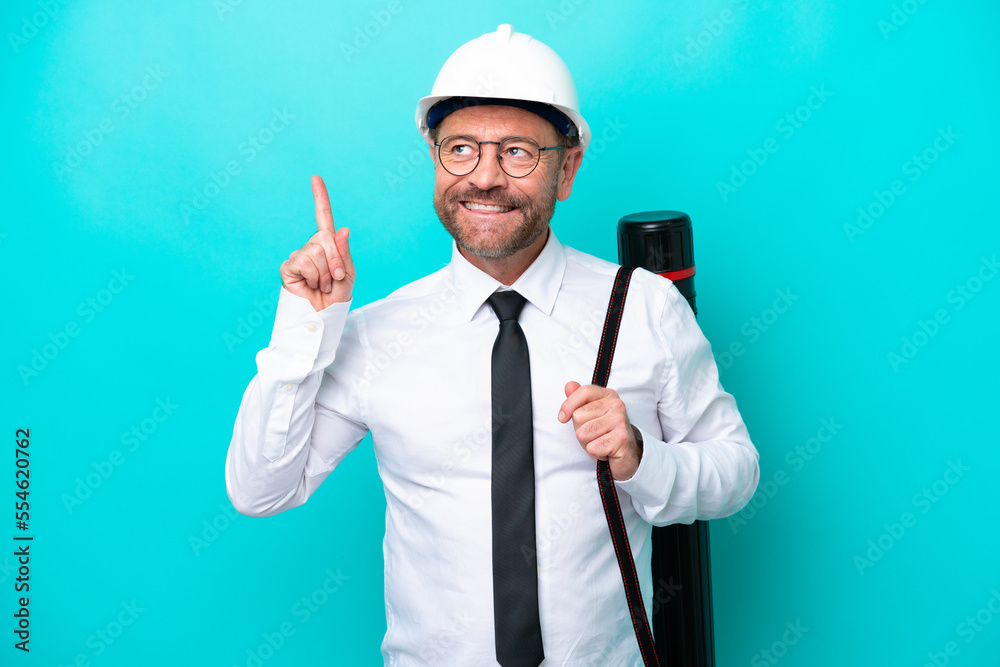 Middle age architect man with helmet and holding blueprints isolated on blue background pointing up a great idea Middle age architect man with helmet and holding blueprints isolated on blue background pointing up a great idea