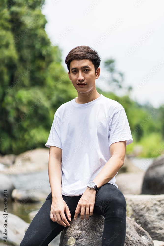 Fototapeta premium An Asian Man With White Shirt Posing Near a River in the Nature