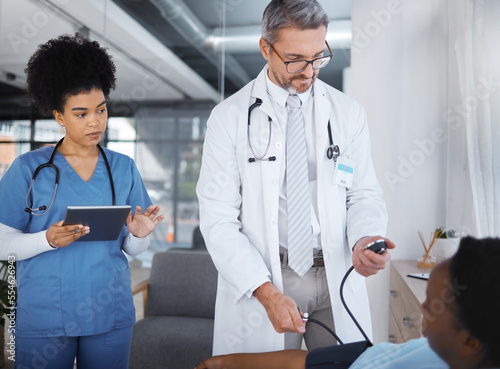 Photography Doctor, patient and blood pressure in clinic with nurse, tablet and analysis for teamwork, health or job