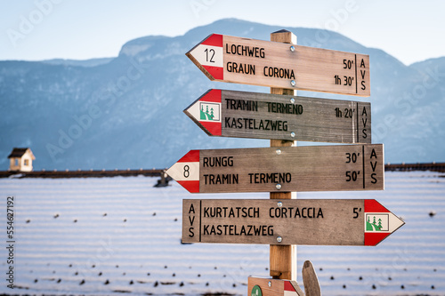 Wooden footpath sign indicating public footpaths in the Village of Cortaccia on the wine road, South Tyrol - Trentino Alto Adige, northern Italy - Europe photo