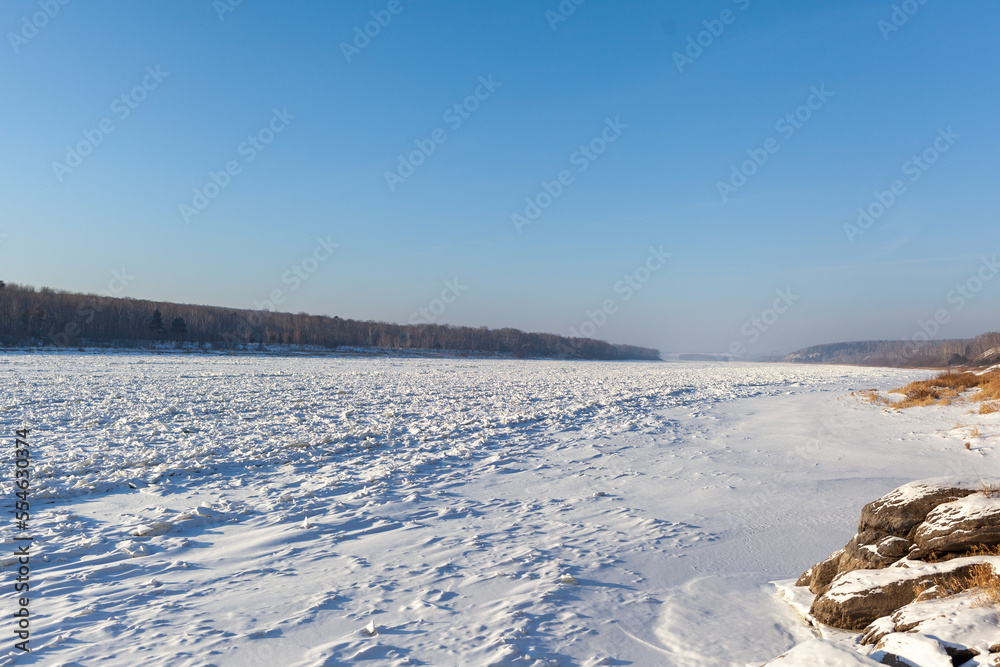 A frozen lake or river in winter. Near the forest and mountains in the snow. Beautiful winter landscapes. Winter trips in nature. A frozen lake or river in winter. Near the forest and mountains in the snow. Beautiful winter landscapes. Winter trips in nature.