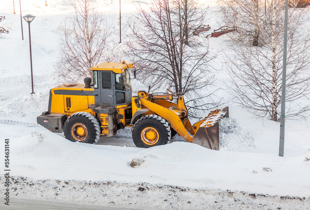 Snow clearing. Tractor clears the way after heavy snowfall. A large orange tractor removes snow from the road and clears the sidewalk. Cleaning roads in the city from snow in winter. Snow clearing. Tractor clears the way after heavy snowfall. A large orange tractor removes snow from the road and clears the sidewalk. Cleaning roads in the city from snow in winter.