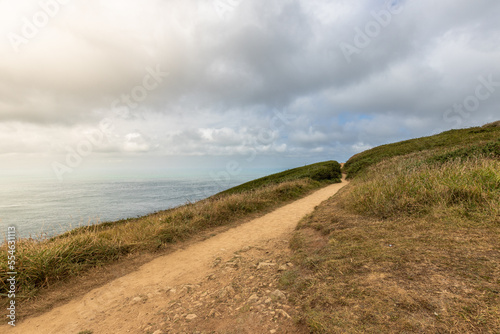 A closeup of a road on a hill with a sea in the background