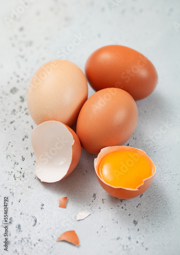 Raw fresh organic eggs with shell and yolk on light kitchen background.