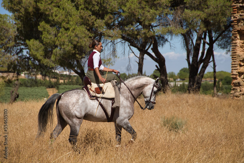 Woman horsewoman, young and beautiful, walking, riding her horse, in the countryside. Concept horse riding, animals, dressage, horsewoman, cowgirl.