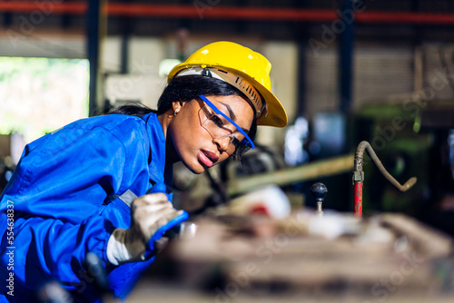 Fotografia Professional labor machanic engineer technician worker industrial african black woman wearing blue safety uniform working control with heavy machine in factory production line