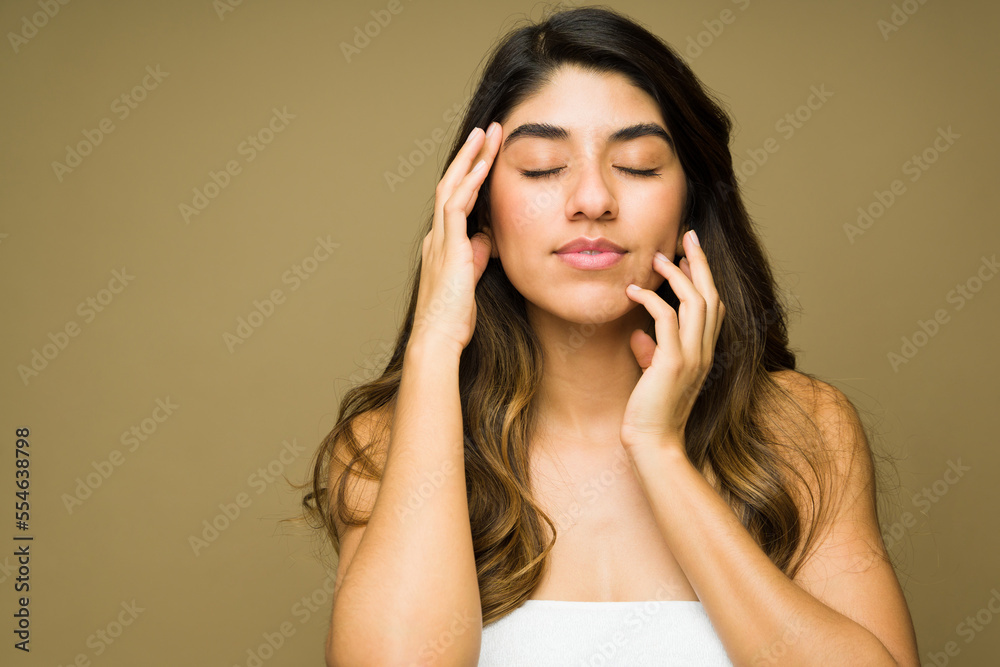 Hispanic woman relaxing while doing her skin care routine Hispanic woman relaxing while doing her skin care routine