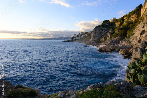 Rocky coastline of the sea at sunset, seascape, view from the shore. Landscape with water, mountains and blue sky outdoors.