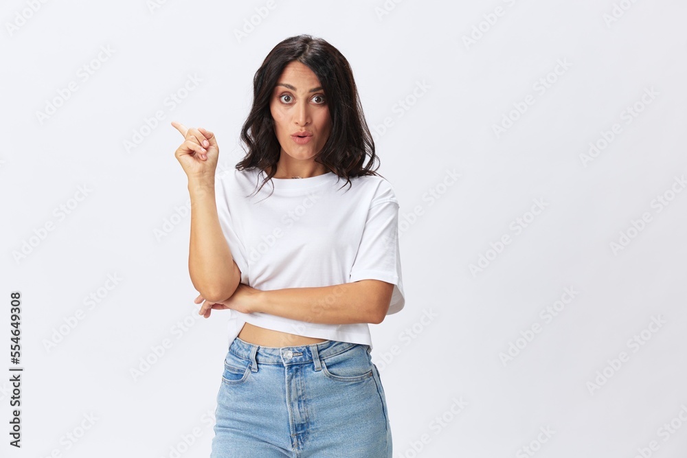 Woman in white t-shirt on white background brunette hands up gestures and signals poses in jeans emotion, lifestyle smiles, copy space Woman in white t-shirt on white background brunette hands up gestures and signals poses in jeans emotion, lifestyle smiles, copy space