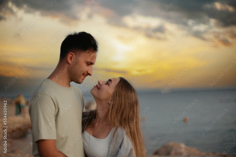young couple in love at sunset by the sea walk along the seashore. Romantic trip to the resort. young couple in love at sunset by the sea walk along the seashore. Romantic trip to the resort.