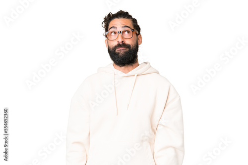 Young man with beard over isolated chroma key background having doubts while looking up