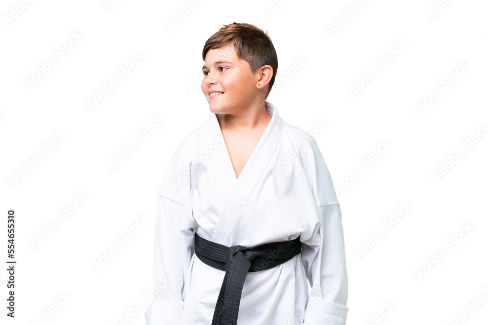 Little caucasian kid doing karate over isolated chroma key background looking side Little caucasian kid doing karate over isolated chroma key background looking side