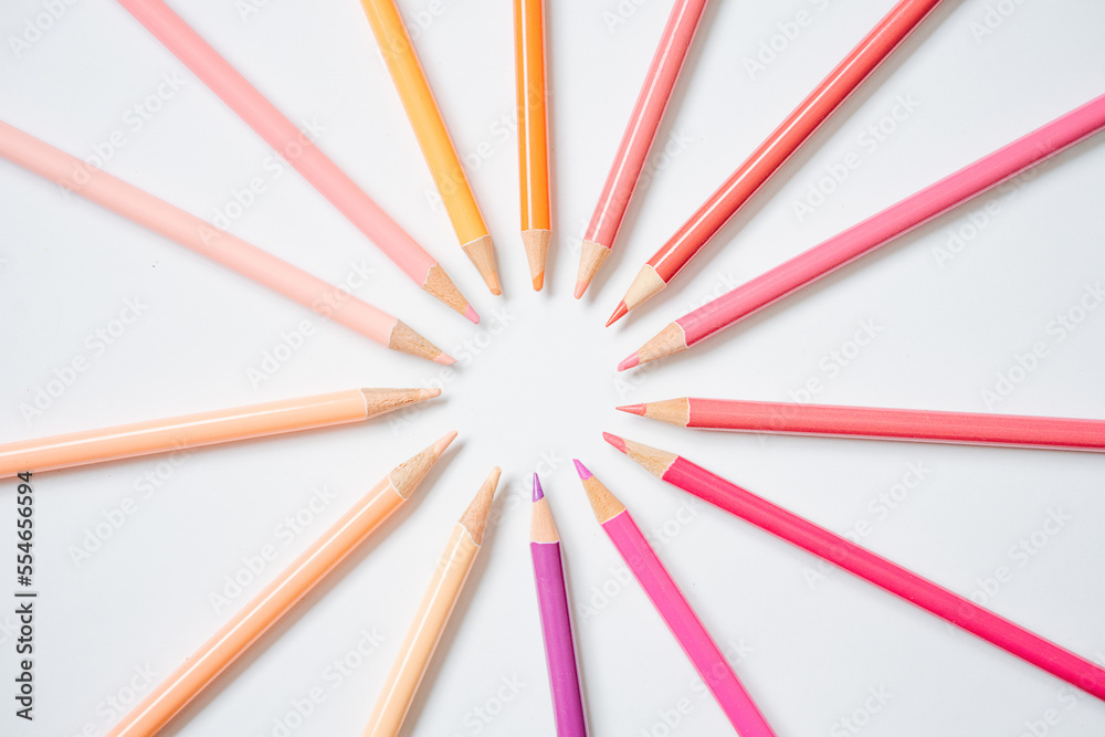 Composition of warm colored pencils paced in solar pattern over white