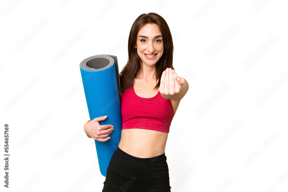 Young sport caucasian woman going to yoga classes while holding a mat over isolated chroma key background inviting to come with hand. Happy that you came Young sport caucasian woman going to yoga classes while holding a mat over isolated chroma key background inviting to come with hand. Happy that you came