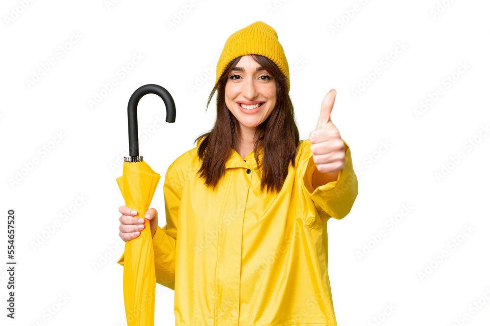 Young caucasian woman with rainproof coat and umbrella over isolated chroma key background with thumbs up because something good has happened Young caucasian woman with rainproof coat and umbrella over isolated chroma key background with thumbs up because something good has happened