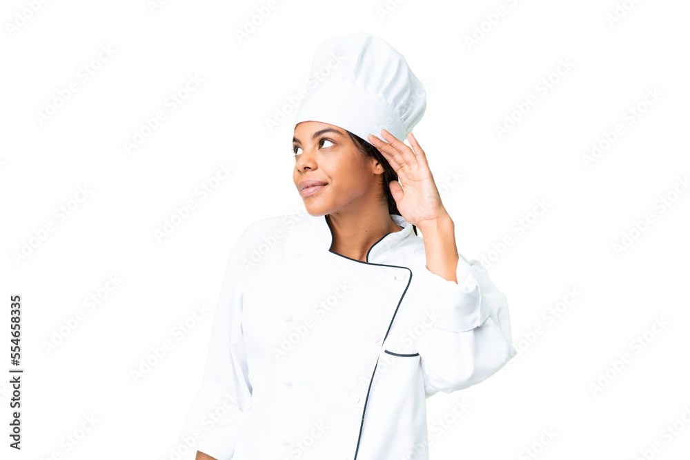 Young African American chef over isolated chroma key background listening to something by putting hand on the ear Young African American chef over isolated chroma key background listening to something by putting hand on the ear
