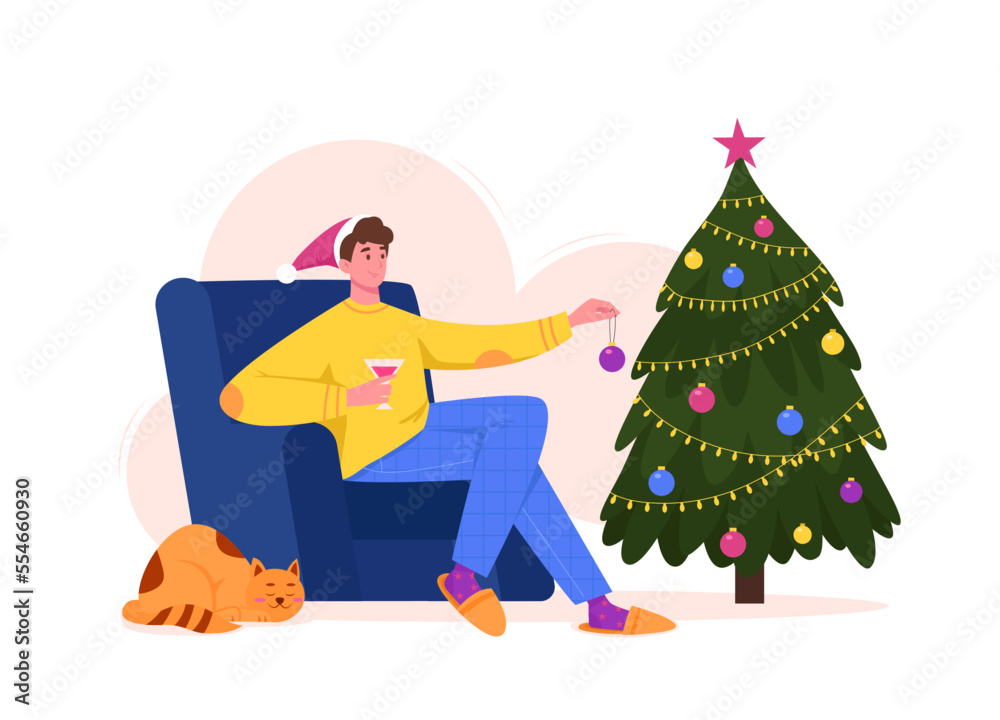 Young man in chair decorating Christmas tree with bauble Young man in chair decorating Christmas tree with bauble