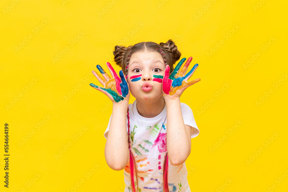A little girl stained in multicolored paints is fooling around.  Children's creativity, drawing. Draw with your hands. The art of creating paintings for schoolchildren. - obrazy, fototapety, plakaty 