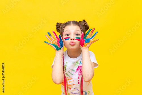 A little girl stained in multicolored paints is fooling around Fototapeta