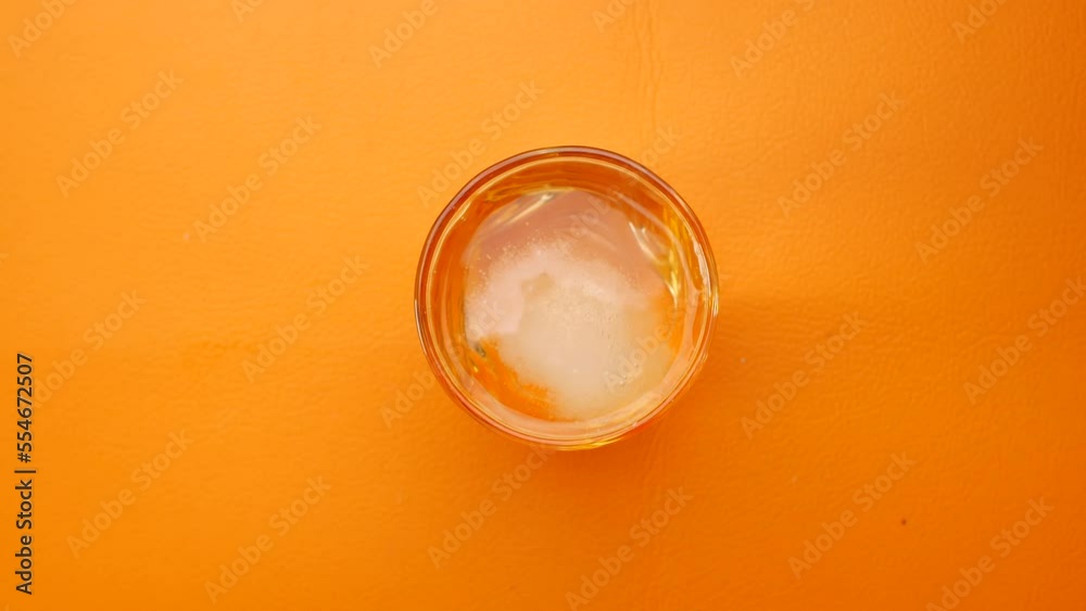 putting Effervescent soluble tablet in a glass of water on orange background putting Effervescent soluble tablet in a glass of water on orange background
