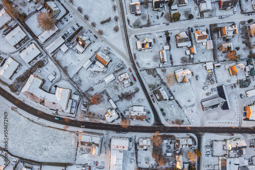Aerial view on little European village in Sweden in winter, many private houses. Snowy weather, sunset. Warm sunlight. 