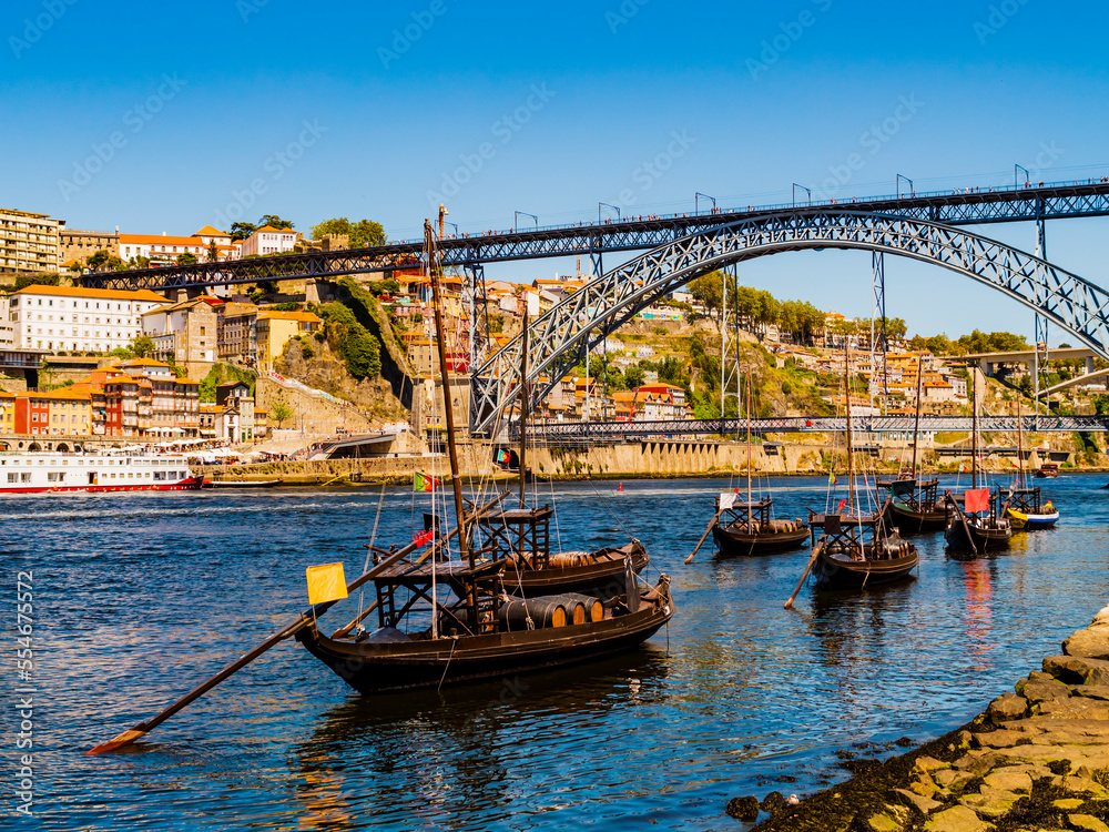 Amazing view of Porto, with its typical boats on the banks of Douro river and the Dom Luis I bridge in background, Portugal

