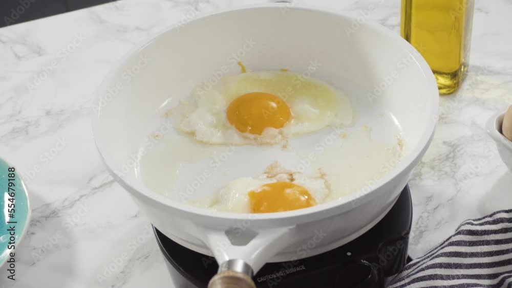 Close up view. Frying farm fresh eggs in a white skillet. Close up view. Frying farm fresh eggs in a white skillet.