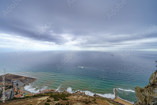 Large expanse of sea by the rock of Gibraltar with cargo ships sailing off the coast.
