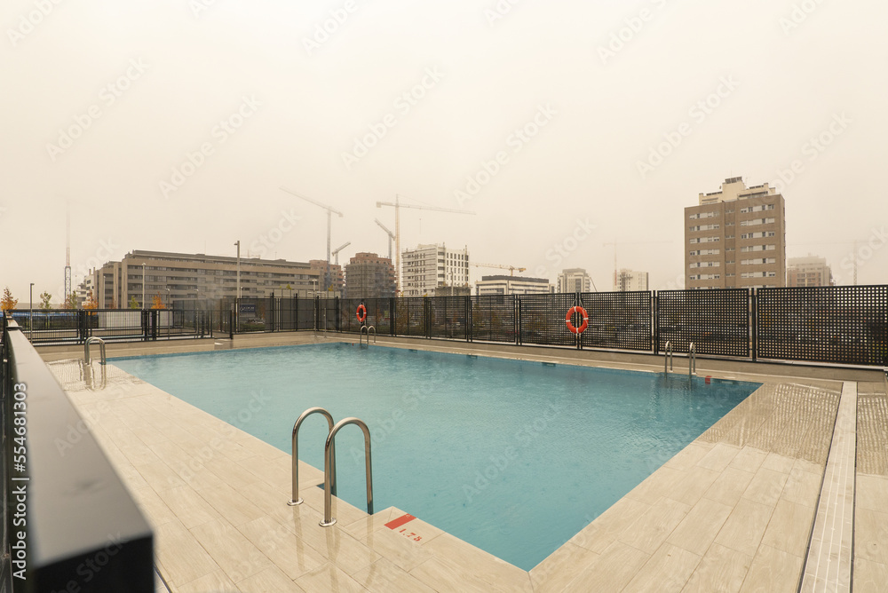 A newly built rectangular community pool in a new area of the city on a torrential rainy day