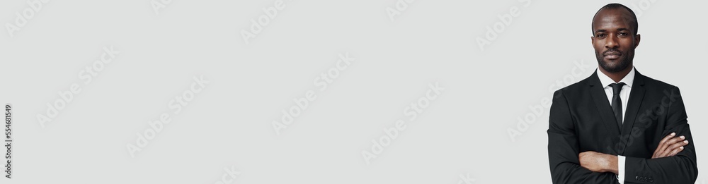 Handsome young African man in formalwear looking at camera while standing against grey background Handsome young African man in formalwear looking at camera while standing against grey background