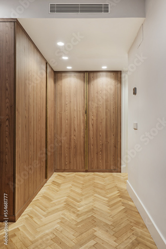 Wooden wardrobe with smooth doors in a room with herringbone oak flooring, spotlights in the false ceiling and ducted air conditioning © Toyakisfoto.photos
