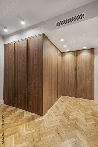 Wardrobe with root wood doors with full-length handles in the room with herringbone oak flooring, false ceiling spotlights and ducted air conditioning