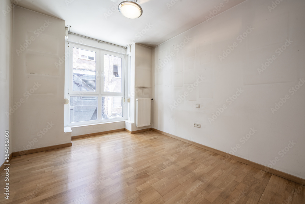 Empty living room with viewpoint to the street with white aluminum structure, white aluminum radiators and oak flooring Empty living room with viewpoint to the street with white aluminum structure, white aluminum radiators and oak flooring