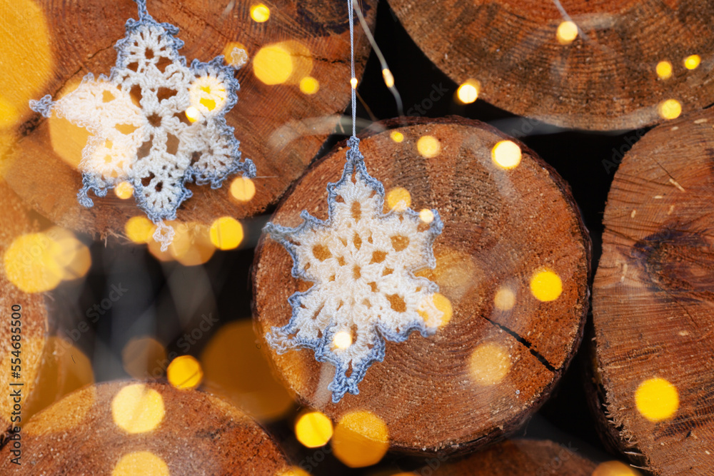 crocheted snowflakes decorations for the Christmas tree on the background of slices of large trees and bright led lanterns crocheted snowflakes decorations for the Christmas tree on the background of slices of large trees and bright led lanterns