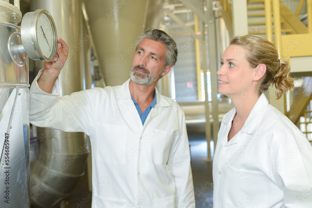 Obraz premium Man and woman looking at gauge on vat