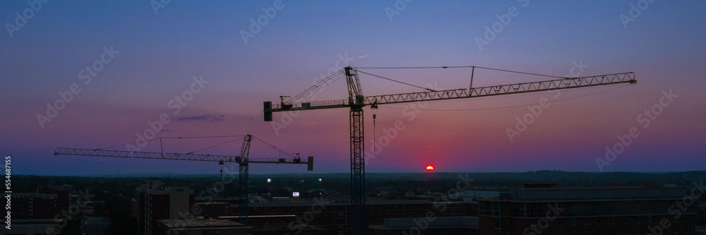 Panorama Construction Crane over college campus with sunset dawn blue red purple skyline