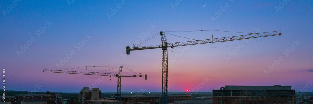 Panorama Construction Crane over college campus with sunset dawn blue red purple skyline Panorama Construction Crane over college campus with sunset dawn blue red purple skyline
