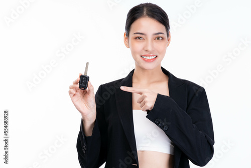 Happy young smiling satisfied successful Asian business woman in suit point finger to car key with smile face isolated on white background and copy space studio portrait Sale female hold car key