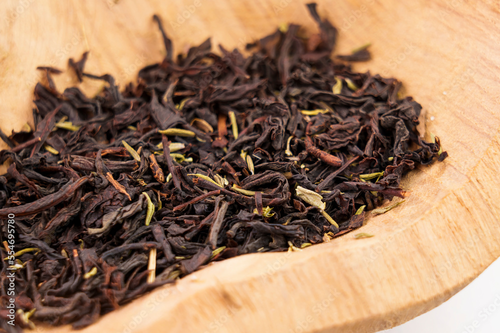 Dried black tea leaves with thyme herb in rustic wooden bowl Dried black tea leaves with thyme herb in rustic wooden bowl