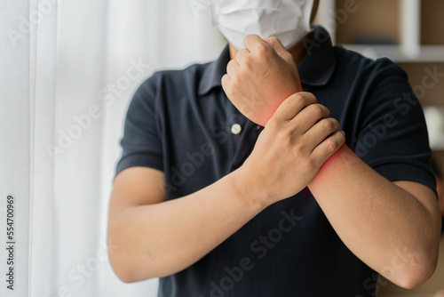 Young Asian man holding his wrist sore from long hours of computer work or the concept of Office syndrome