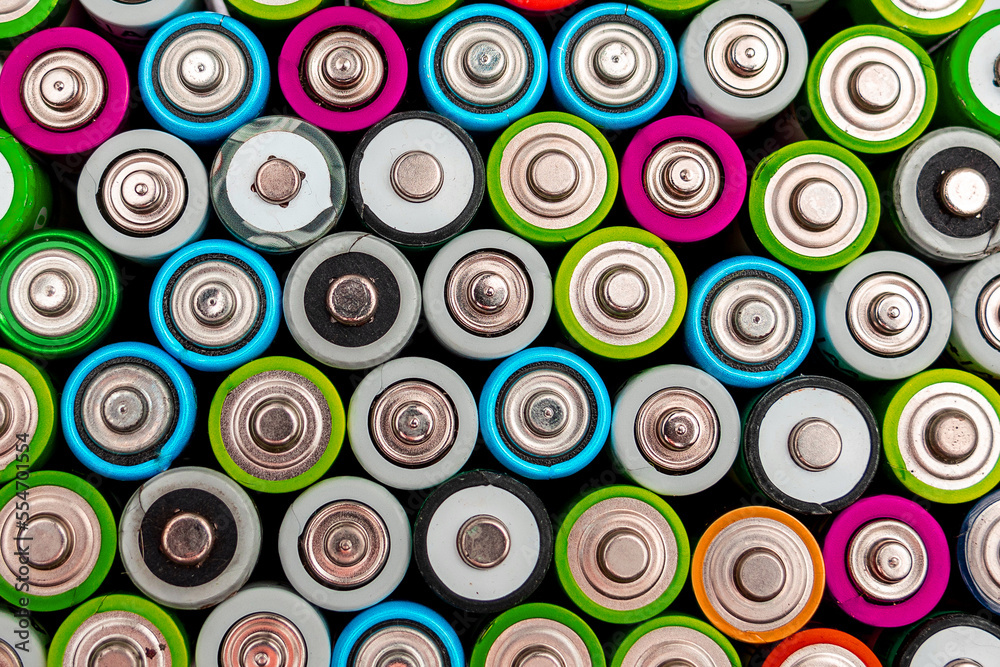 Energy abstract background of colorful batteries. Close up top view on rows of selection of AA batteries. Alkaline battery aa size. Several batteries are next to each other. Many aa batteries. Energy abstract background of colorful batteries. Close up top view on rows of selection of AA batteries. Alkaline battery aa size. Several batteries are next to each other. Many aa batteries.