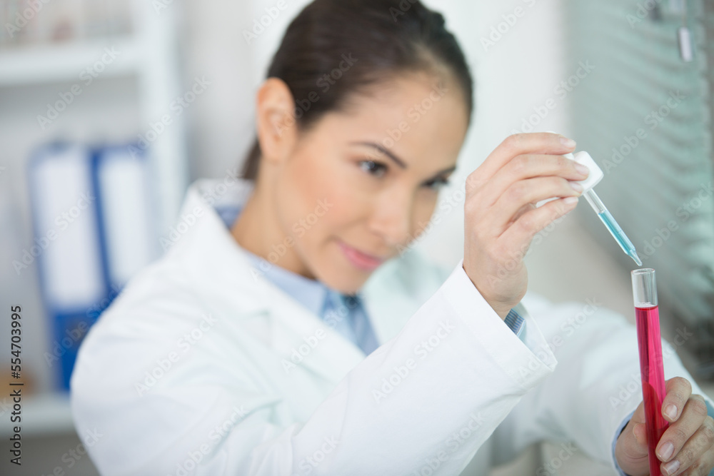 female scientist dropping solution into a test-tube female scientist dropping solution into a test-tube
