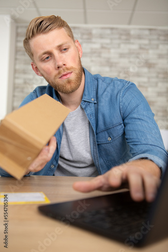 man with laptop and cardboard box at home
