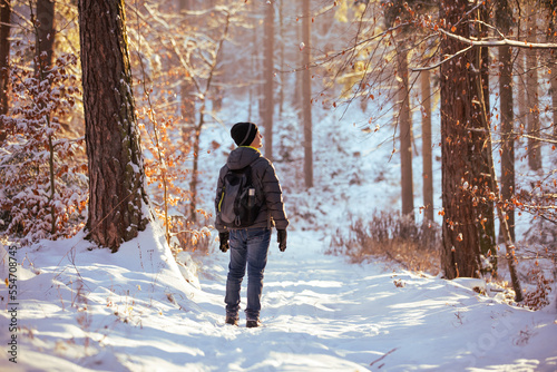 turysta z plecakiem wędrujący po zaśnieżonym lesie zimą 