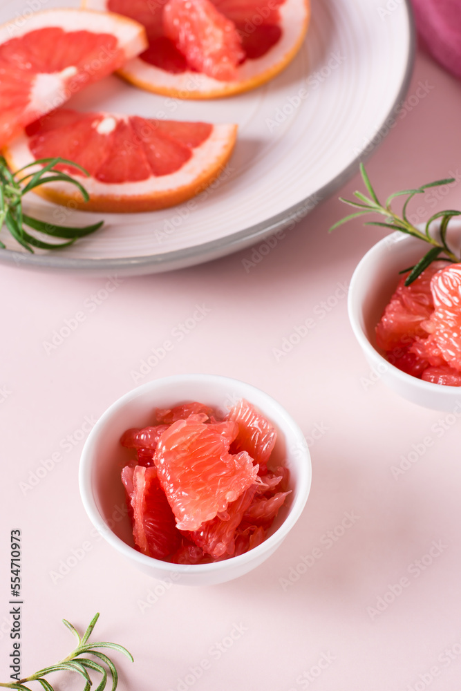 Juicy grapefruit slices and rosemary in a bowl on the table. Cocktail ingredients. Vertical view Juicy grapefruit slices and rosemary in a bowl on the table. Cocktail ingredients. Vertical view