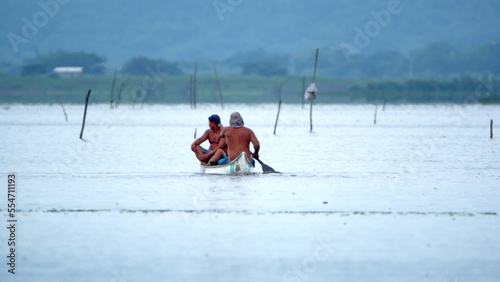 Two men paddling a boat in the La Segua wetlands near Chone, Ecuador photo