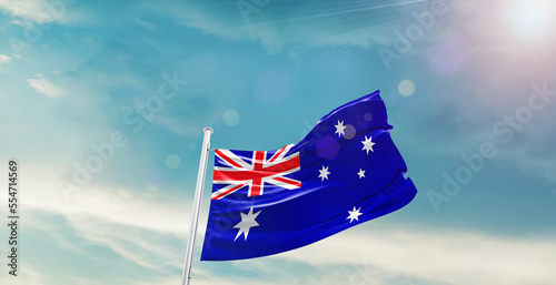 waving flag of Australia in blue sky. the symbol of the state on wavy cotton fabric.