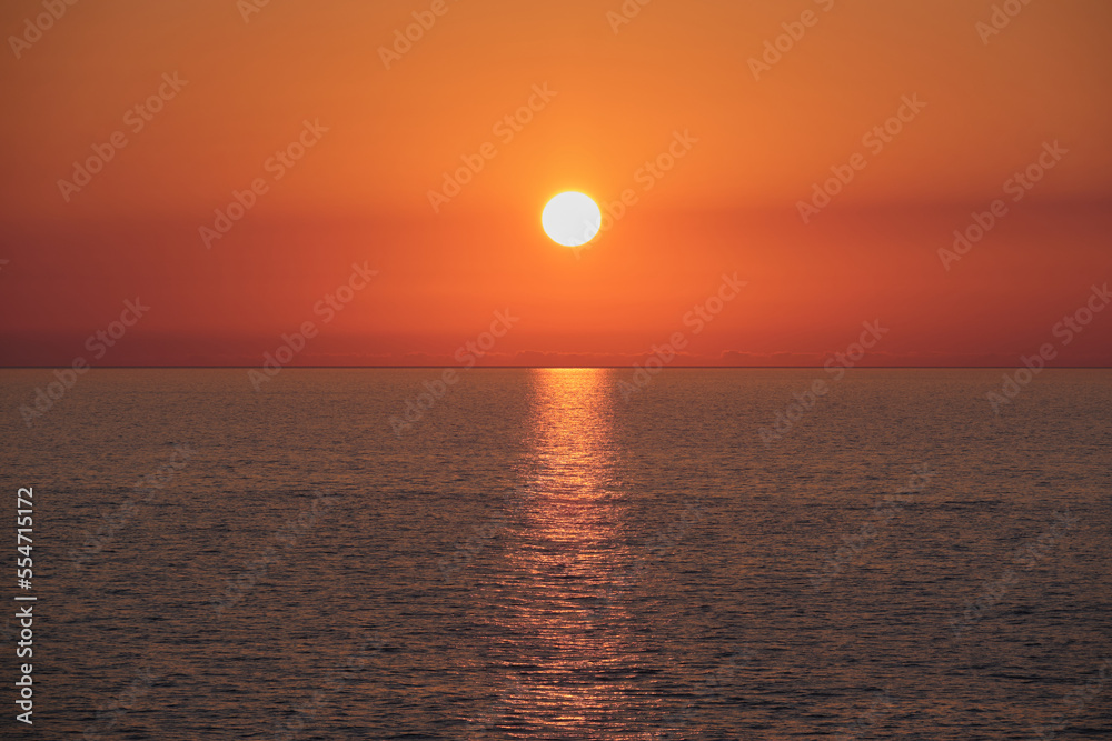 Bright sunrise with big yellow sun under the surface of the sea